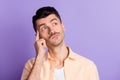 Photo of pensive minded guy finger temple look empty space wear beige shirt isolated violet color background