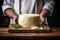 Photo of a person cutting cheese on a wooden cutting board