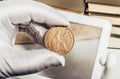 Photo of a person\'s hand in gloves holding a british coin