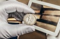 Photo of a person's hand in gloves holding a silver soviet coin