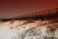 Photo of a pier jutting out over the sandy beach.