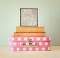 Photo of pink suitcase with polkadots and stack of books over wooden table, retro style image