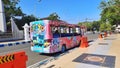 Photo of a pink tour bus with a cartoon image parked on the side of the street in the city square of Pacitan.