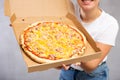 Photo of pizza held by smiling young woman against gray background Royalty Free Stock Photo