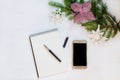 Photo plane smartphone or mobile phone, a notebook for notes, pens and decorated tree branch on a white wooden background. Flat la