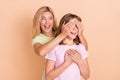 Photo of playful happy mother and daughter hands cover eyes game guess amazed isolated on beige color background