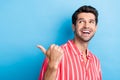 Photo of pleasant satified man with bristle dressed striped shirt look directing at sale empty space isolated on blue