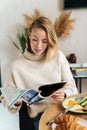 Photo of pleased blonde woman reading magazine while having breakfast Royalty Free Stock Photo