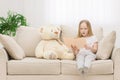 Photo of plush teddy bear and little girl holding a book on sofa. Royalty Free Stock Photo