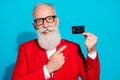 Photo portrait aged man in glasses pointing finger bank card smiling isolated bright blue color background