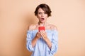 Photo portrait of angry offended woman holding phone in two hands isolated on pastel beige colored background