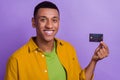 Photo portrait of attractive young male holding credit card bank client wear trendy yellow garment isolated on purple Royalty Free Stock Photo