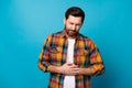 Photo portrait of attractive young man touch stomach feel pain wear trendy plaid clothes isolated on blue color Royalty Free Stock Photo