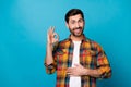 Photo portrait of attractive young man touch stomach show okey symbol dressed stylish checkered clothes isolated on blue Royalty Free Stock Photo