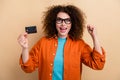 Photo portrait of attractive young woman credit card raise fist celebrate dressed stylish orange clothes isolated on Royalty Free Stock Photo