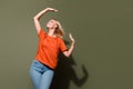Photo portrait of attractive young woman fluttering hair raise hands dressed stylish orange clothes isolated on khaki