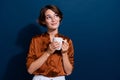 Photo portrait of attractive young woman hold coffee mug look empty space wear trendy brown blouse isolated on dark blue Royalty Free Stock Photo