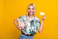 Photo portrait of attractive young woman hold credit card pig dressed stylish leaves print clothes isolated on yellow Royalty Free Stock Photo