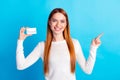 Photo portrait of attractive young woman hold credit card point empty space dressed stylish white clothes isolated on Royalty Free Stock Photo