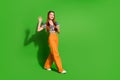 Photo portrait of attractive young woman hold telephone walk wave hand dressed stylish retro clothes isolated on green Royalty Free Stock Photo