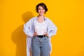 Photo portrait of beautiful female millennial smiling wearing white shirt jeans isolated on vivid yellow color