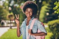 Photo portrait of black skinned curly girl smiling happily showing v-sign with two fingers wearing denim shirt pink Royalty Free Stock Photo