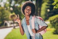 Photo portrait of black skinned girl smiling showing v-sign with two fingers laughing wearing denim shirt pink casual Royalty Free Stock Photo