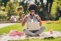Photo portrait of black skinned girl using computer in park smiling showing thumb-up gesture like sign sitting near bag Royalty Free Stock Photo