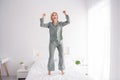 Photo portrait of blonde attractive young woman jumping bed have fun dressed stylish gray pajama light modern bedroom Royalty Free Stock Photo