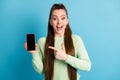 Photo portrait of brunette girl pointing finger at phone with blank space open mouth isolated on pastel blue colored Royalty Free Stock Photo