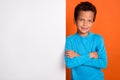 Photo portrait of charming little schoolboy folded arms white blank advert wall wear trendy blue look isolated on orange
