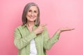 Photo portrait of charming senior woman grey hair advertiser direct finger holding palm new vitamins on pink