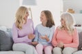 Photo portrait of cheerful mother daughter grandmother talking sitting on sofa at home laughing Royalty Free Stock Photo