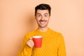 Photo portrait of cheerful smiling man drinking coffee keeping cup isolated on pastel beige color background Royalty Free Stock Photo