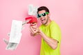 Photo portrait crazy man wearing bright t-shirt shooting with banknotes from gun isolated pastel pink color background
