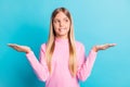 Photo portrait of curious schoolgirl showing copyspaces on hands looking at side isolated on vibrant turquoise color