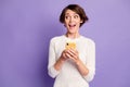 Photo portrait of curious surprised female student keeping cellphone looking at blank space isolated on vivid purple