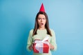 Photo portrait of disgusted woman holding red box wearing cone isolated on pastel blue colored background