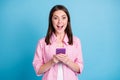 Photo portrait of ecstatic girl holding phone in two hands isolated on pastel blue colored background