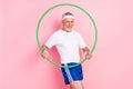 Photo portrait of elder man keeping hoola hoop training in gym doing warm-up isolated pastel pink color background Royalty Free Stock Photo