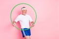 Photo portrait of elder man keeping hoola hoop training in gym doing warm-up looking copyspace isolated pastel pink Royalty Free Stock Photo