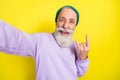 Photo portrait of elder man showing heavy metal sign smiling isolated on bright yellow color background