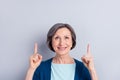 Photo portrait of elder woman curious pointing fingers up copyspace isolated on grey color background