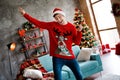 Photo portrait of energetic young man dancing theme party red christmas sweater traditional decorated living room
