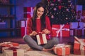 Photo portrait of engaged girl unpacking gift box sitting on floor in lotus pose indoors