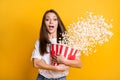 Photo portrait of excited girl throwing pop corn in air watching horror terrified afraid fear isolated vivid yellow