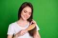 Photo portrait of focused girl brushing hair isolated on vivid green colored background