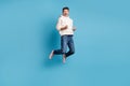 Photo portrait full body view of funny celebrating man jumping up wearing woolen hoodie isolated on pastel blue colored