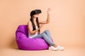 Photo portrait full body view of immersed woman wearing vr headset sitting in beanbag chair isolated on pastel beige Royalty Free Stock Photo