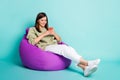 Photo portrait full body view of smiling girl chatting holding phone in two hands sitting in beanbag chair isolated on